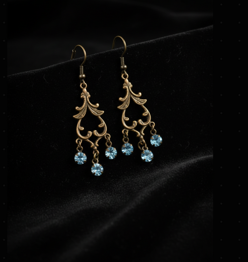 Antique gold Victorian filigree scrollwork chandelier earrings with three light sapphire blue crystal drops on black velvet